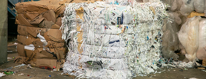 A bundle of recycled paper and a bundle of recycled cardboard next to each other.